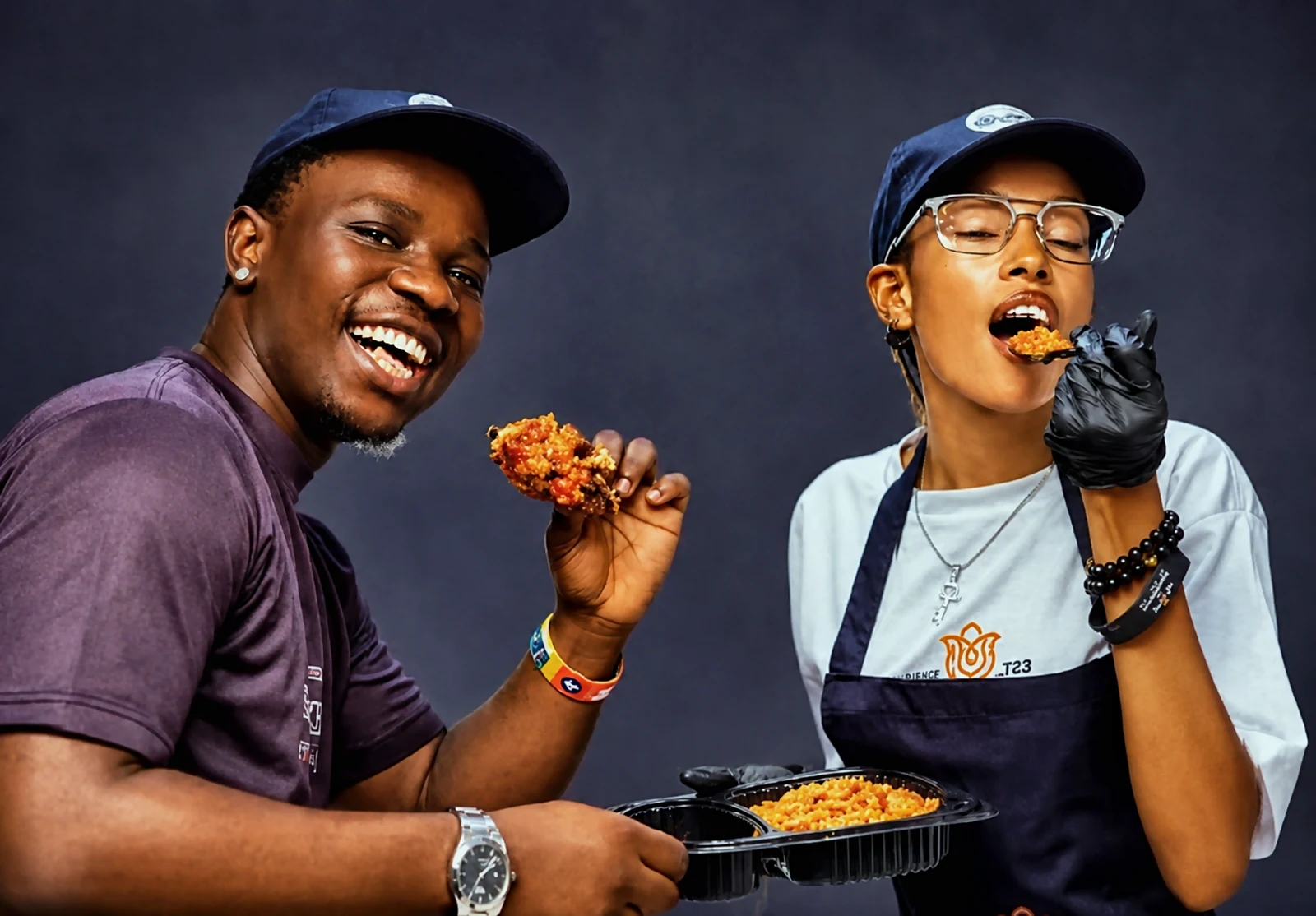 Two happy Y06 customers enjoying a plate of jollof rice and grilled chicken